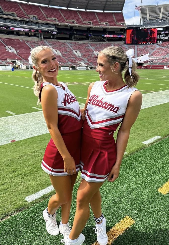 two cheerleaders are standing on the field