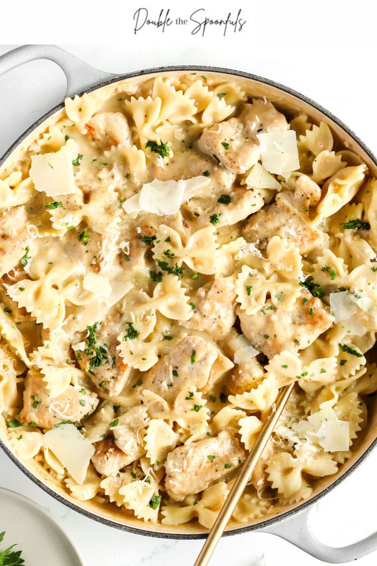 a skillet filled with pasta, meat and parsley on top of a white table