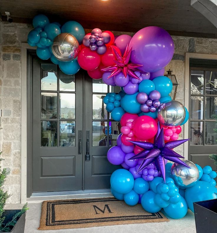 a bunch of balloons that are on the front of a house with a welcome mat