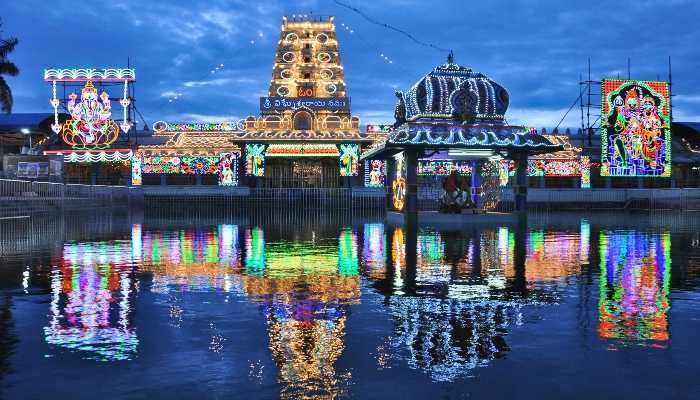 an amusement park is lit up at night with lights on the water and rides in the background