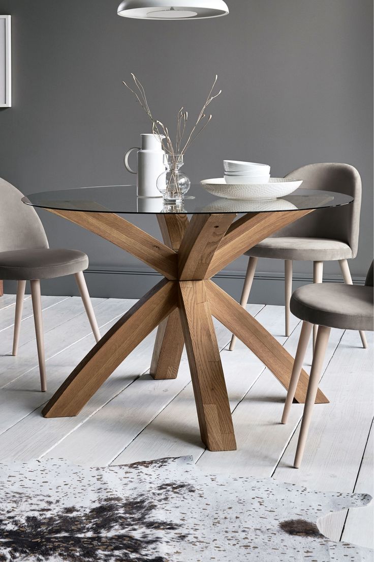 a glass table with four chairs around it and a vase on the table next to it