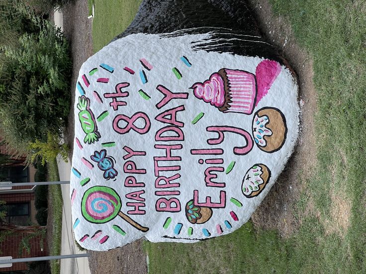 a large rock with the words happy birthday written on it in front of a grassy area