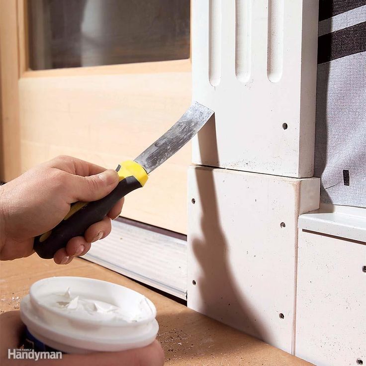 a person using a knife to cut something off the side of a door with a plastic cup next to it