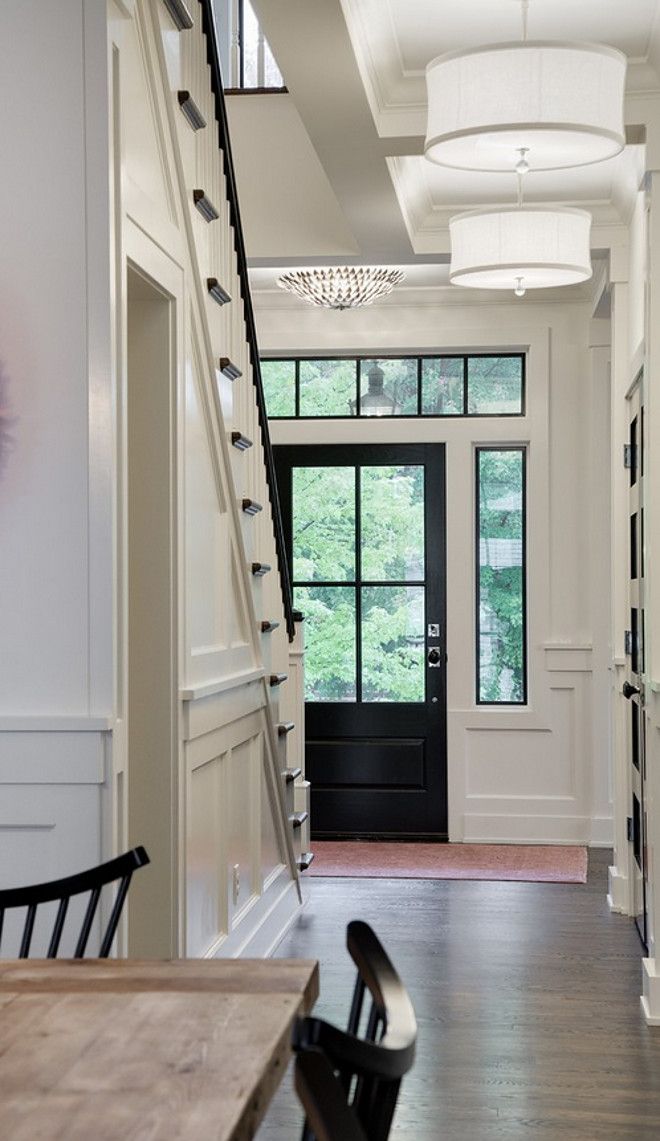 a black door is in front of a white house with stairs leading up to the second floor