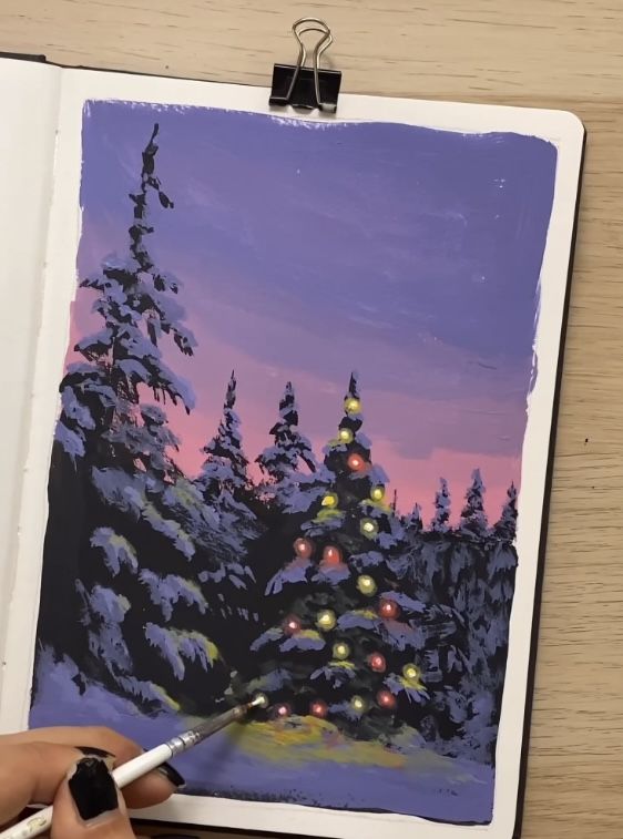 someone is painting a christmas tree with lights in the snow and trees are lit up