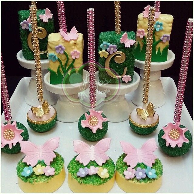 a table topped with lots of cupcakes covered in green and pink icing