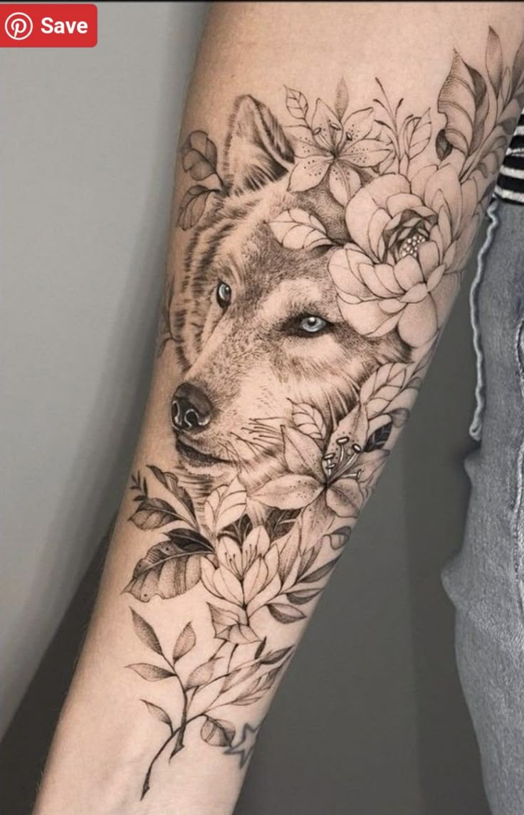 a person with a tattoo on their arm that has flowers and a wolf's head