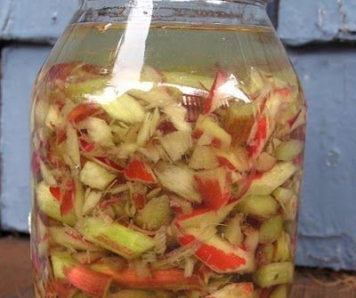 a jar filled with sliced up vegetables sitting on top of a wooden table next to a blue door