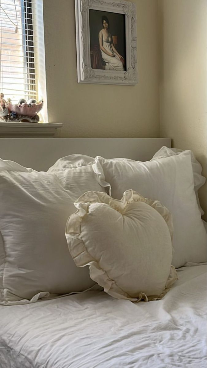 a bed with white pillows on top of it and a framed picture above the headboard