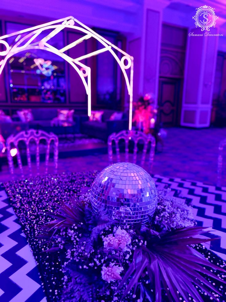 a disco ball sitting on top of a black and white checkered floor next to chairs