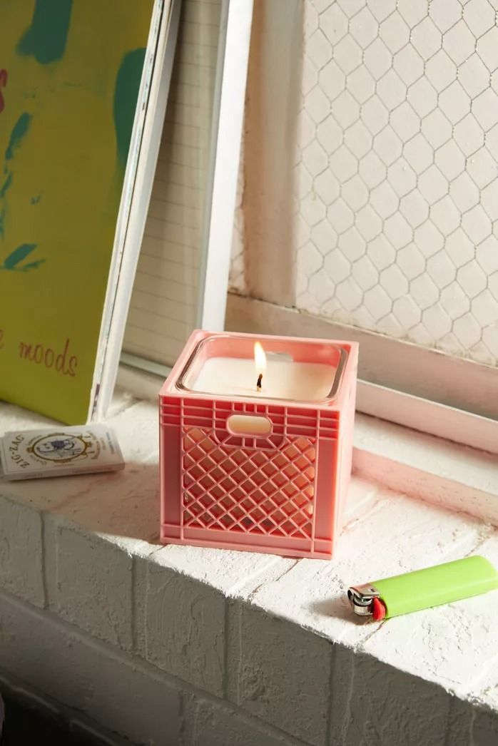 a pink candle sitting on top of a window sill next to a green pen