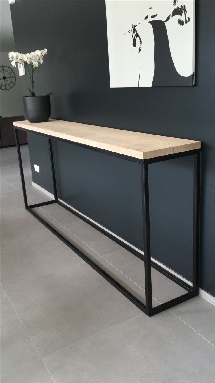 a black and wood console table in front of a gray wall with flowers on it