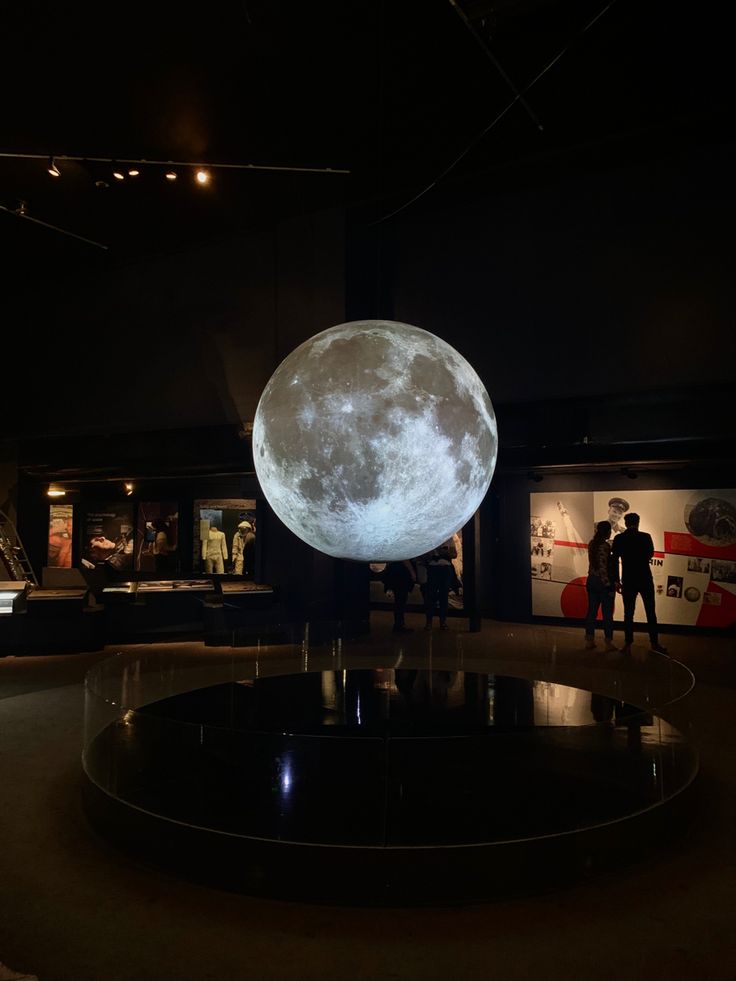 two people standing in front of a giant moon on display at the national museum of american history