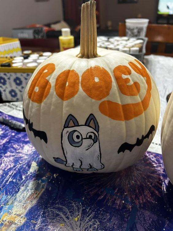 a white pumpkin with an image of a cat on it and the word boo spelled out