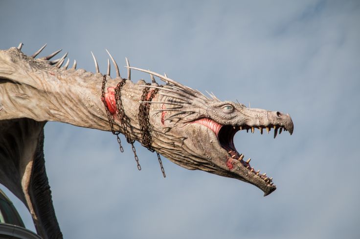 a statue of a dragon with spikes on it's head is shown against a blue sky