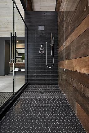 a black tiled bathroom with wooden walls and tile flooring, along with a walk in shower