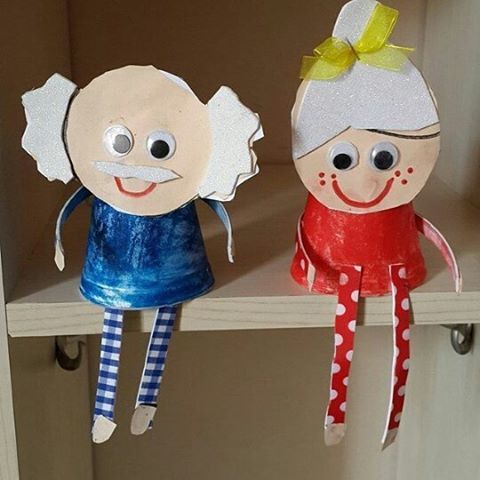 two paper dolls sitting on top of a shelf