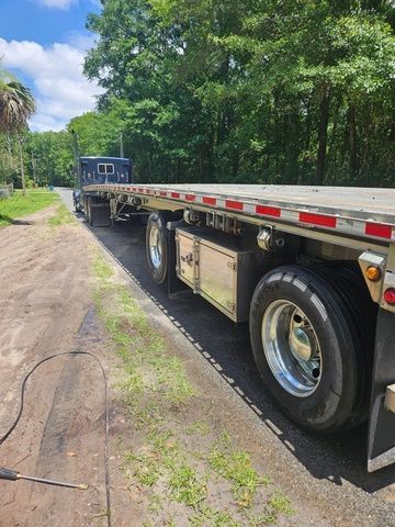 a flatbed truck parked on the side of a dirt road in front of trees