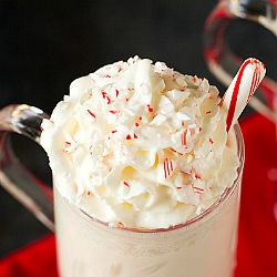 there is a drink with whipped cream and candy canes in the cup on the table