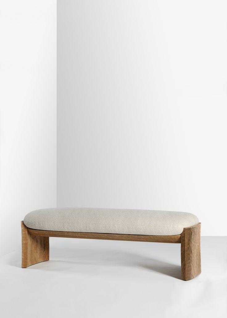 a wooden bench sitting in front of a white wall