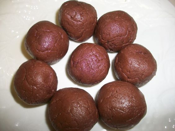 six chocolate balls sitting on top of a white plate