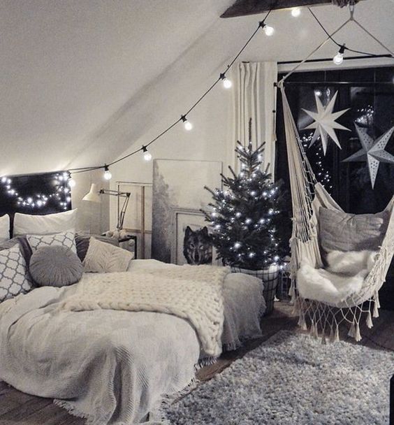 an attic bedroom decorated for christmas with lights and hammock hanging from the ceiling