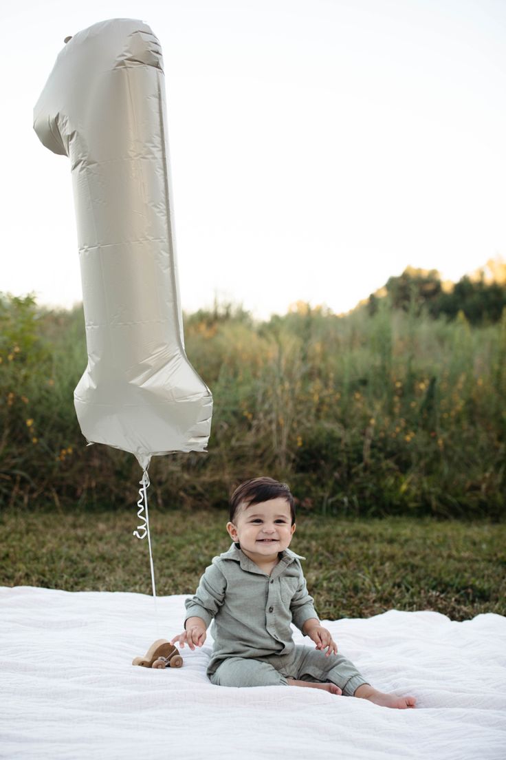 a baby sitting on the ground next to an inflatable balloon