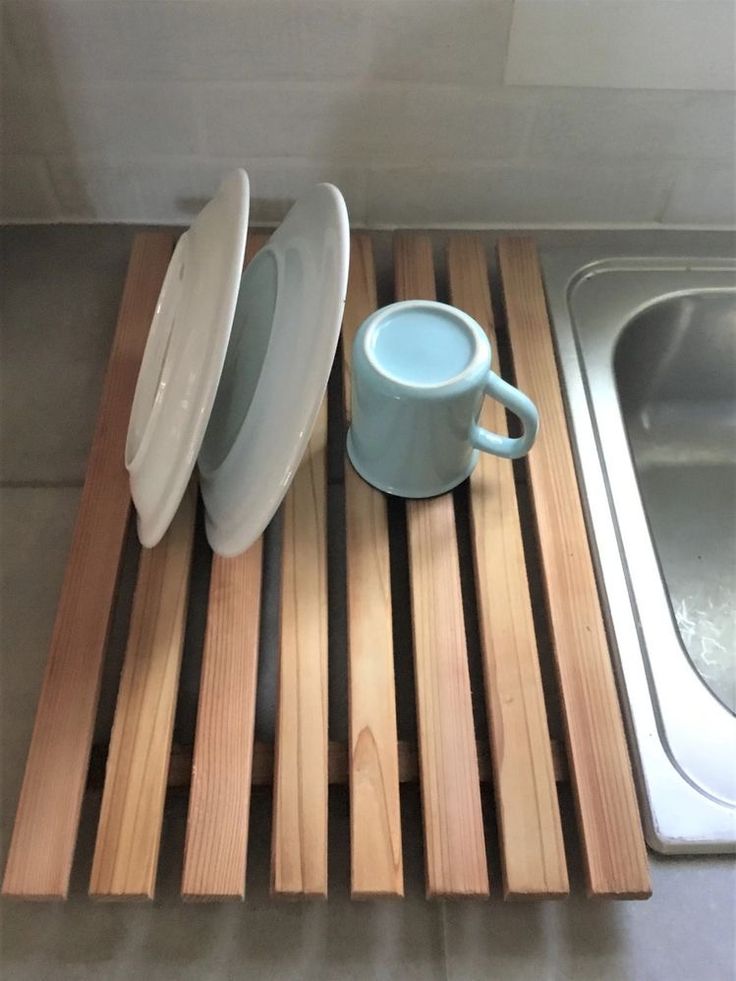 a wooden tray with two plates and a cup sitting on it next to a sink