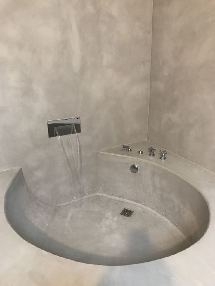 a bathtub with water running from the faucet to the side, in a bathroom