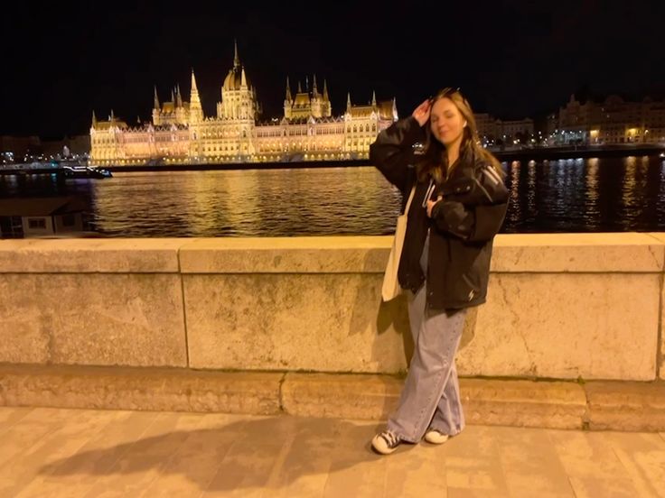 a woman standing next to a river at night