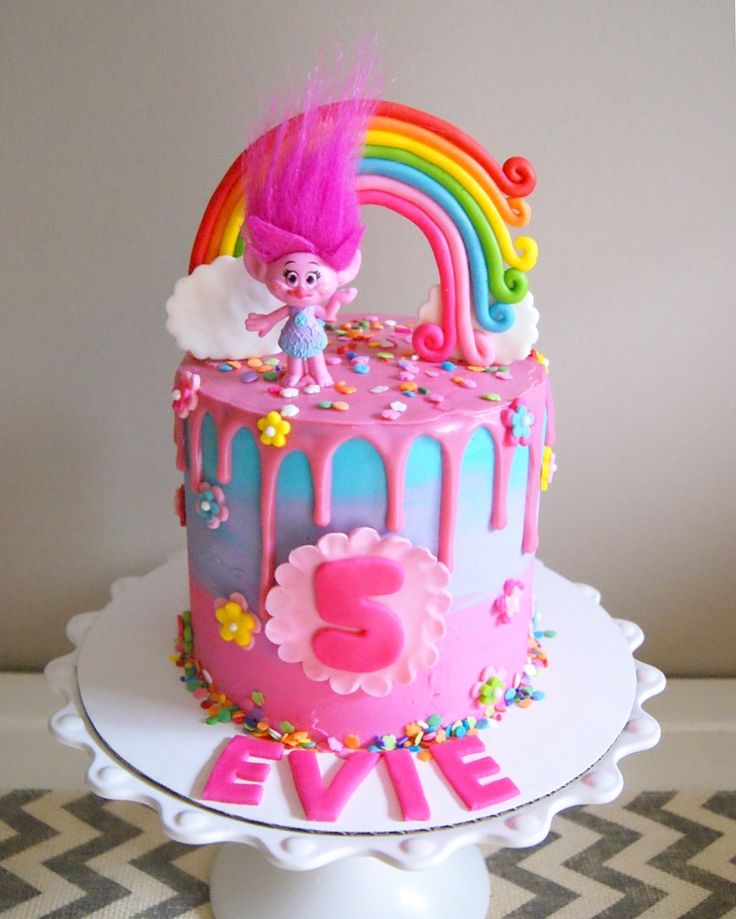 a birthday cake decorated with pink icing and rainbow decorations