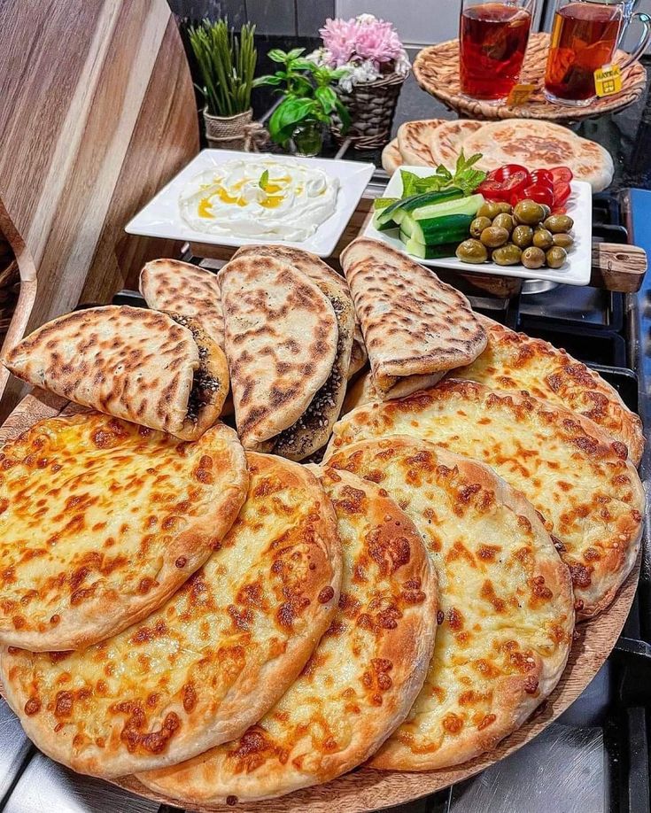 several pizzas are arranged on a table with plates and bowls full of food in the background