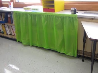 there is a green table in front of the bookshelf