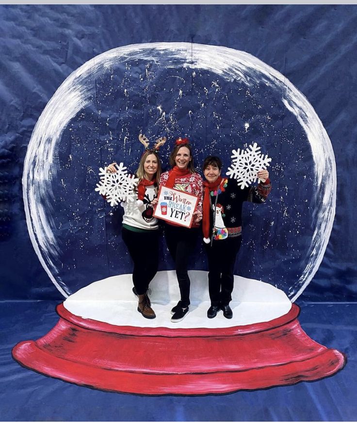 two women and a boy standing in front of a snow globe with christmas decorations on it