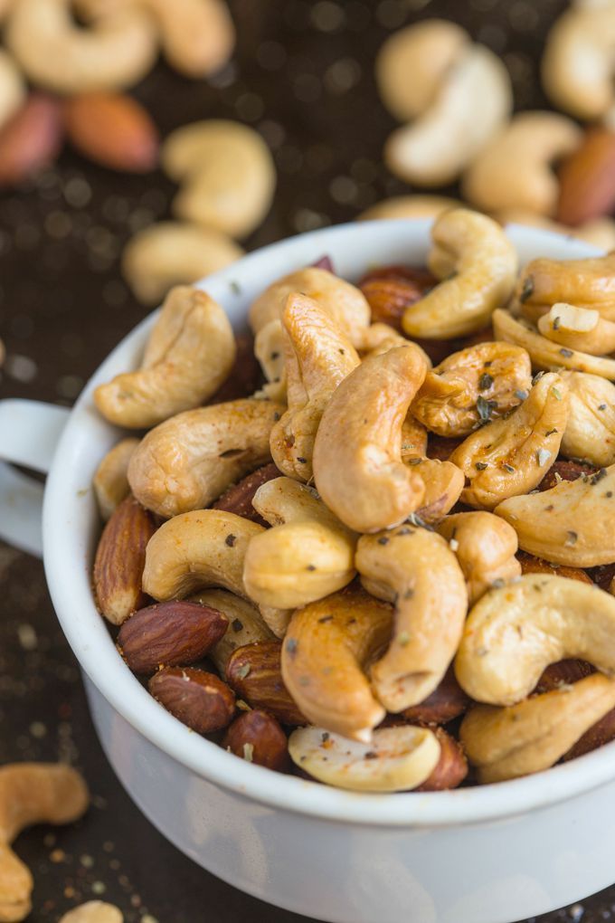 a white bowl filled with cashews sitting on top of a table next to other nuts