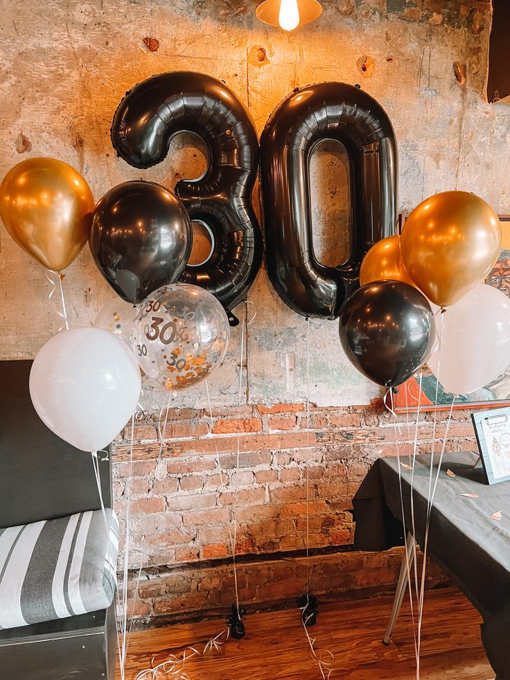 balloons in the shape of the number 30 are on display next to a brick wall