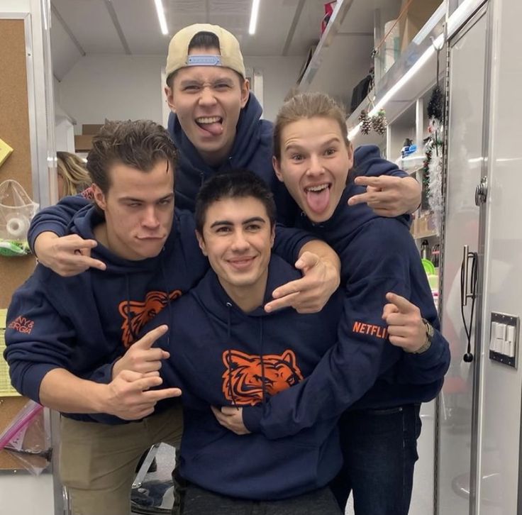 four young men in sweatshirts posing for the camera with their arms around each other