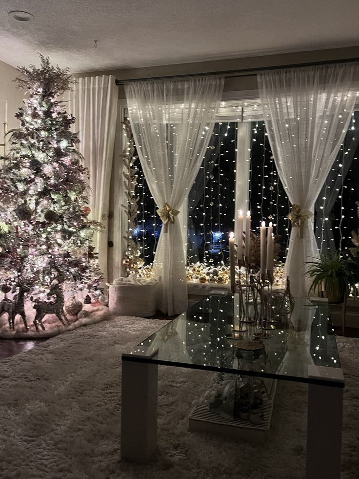 a living room decorated for christmas with a lit tree in the corner and lights on the windows