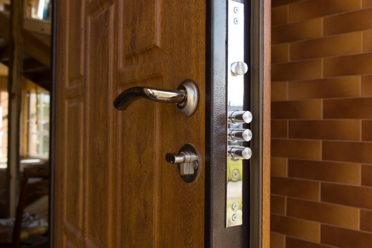 a close up of a wooden door with knobs on it's side and brick wall in the background