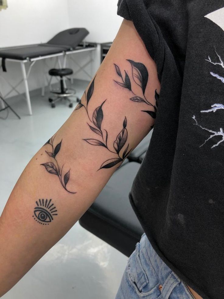 a person with a tattoo on their arm that has leaves and sunbursts