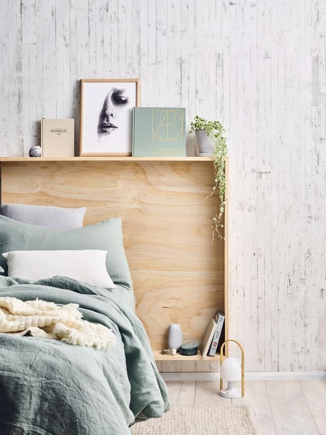 a bed with pillows and blankets on top of it next to a wooden headboard