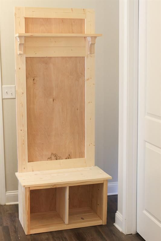 an unfinished wooden bench sitting on top of a hard wood floor next to a white door