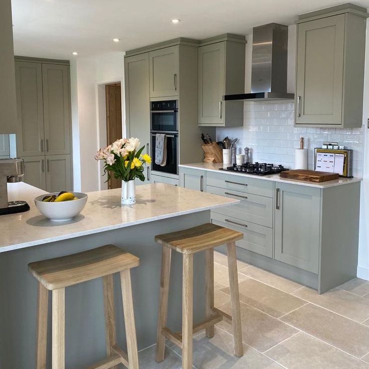 a kitchen with two stools in front of the counter and an island that has flowers on it