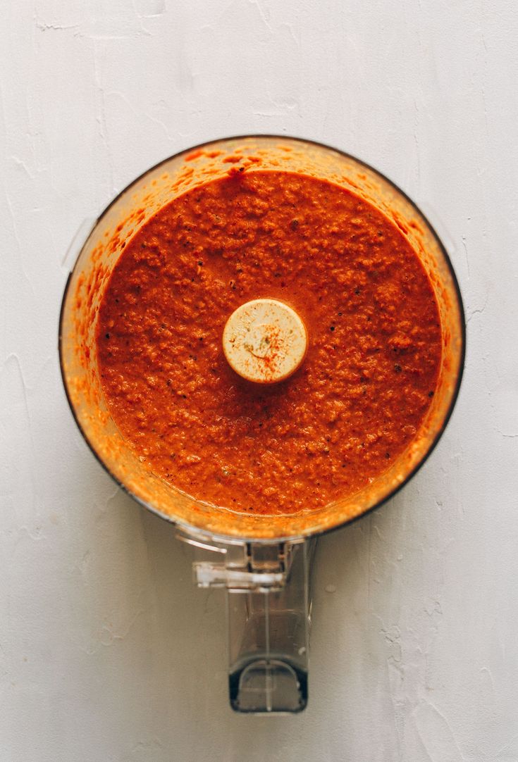 a food processor filled with red sauce on top of a white wall