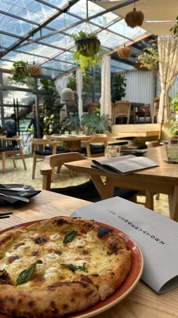 a pizza sitting on top of a red plate next to a table filled with chairs