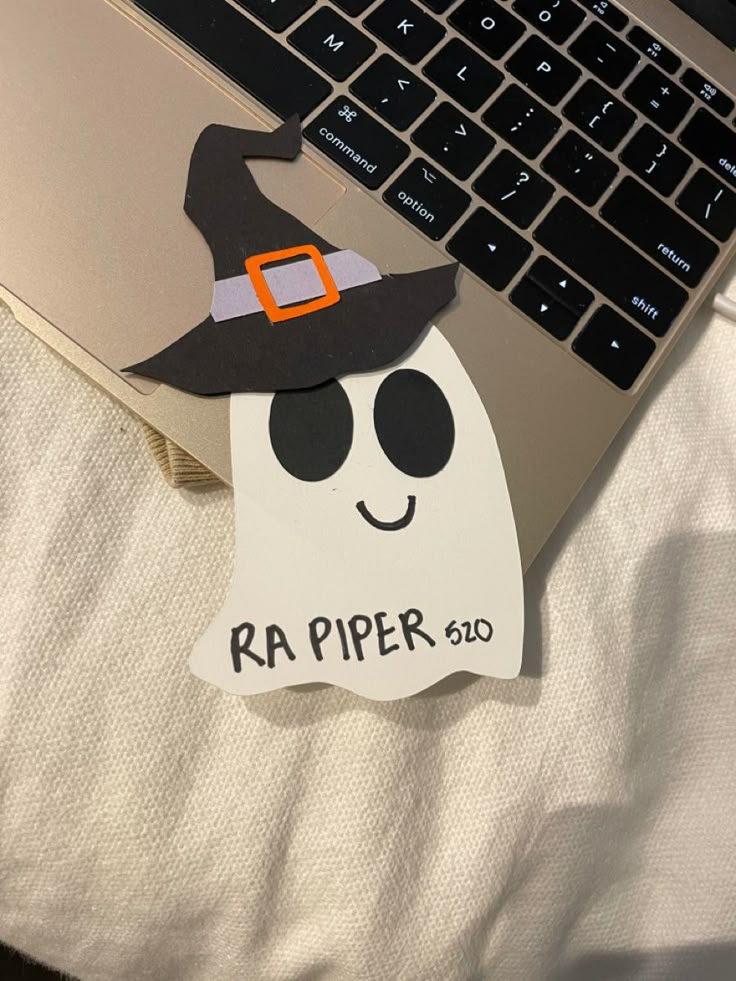 a laptop computer sitting on top of a bed next to a sticker with a witch hat