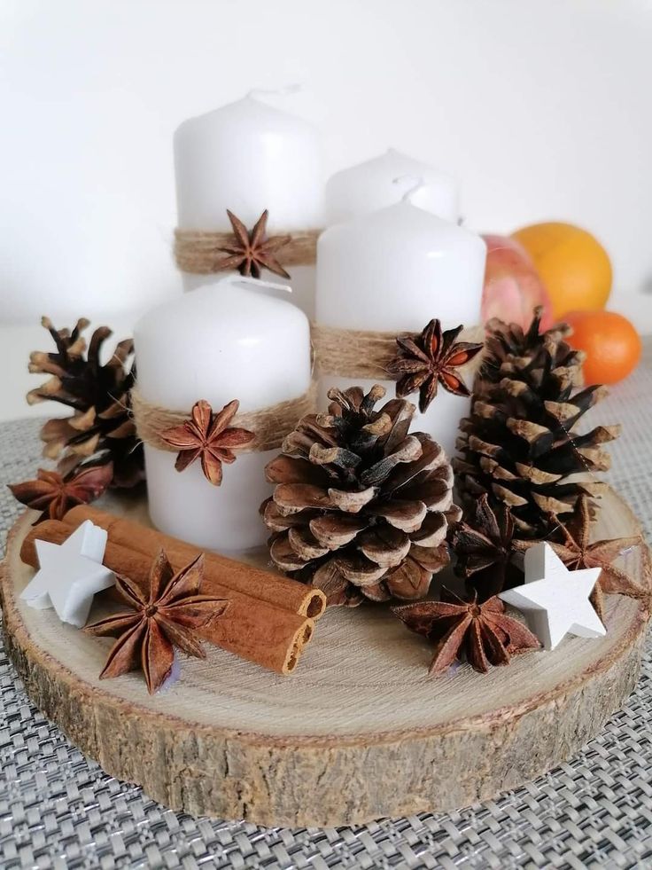 some white candles are sitting on a wood slice