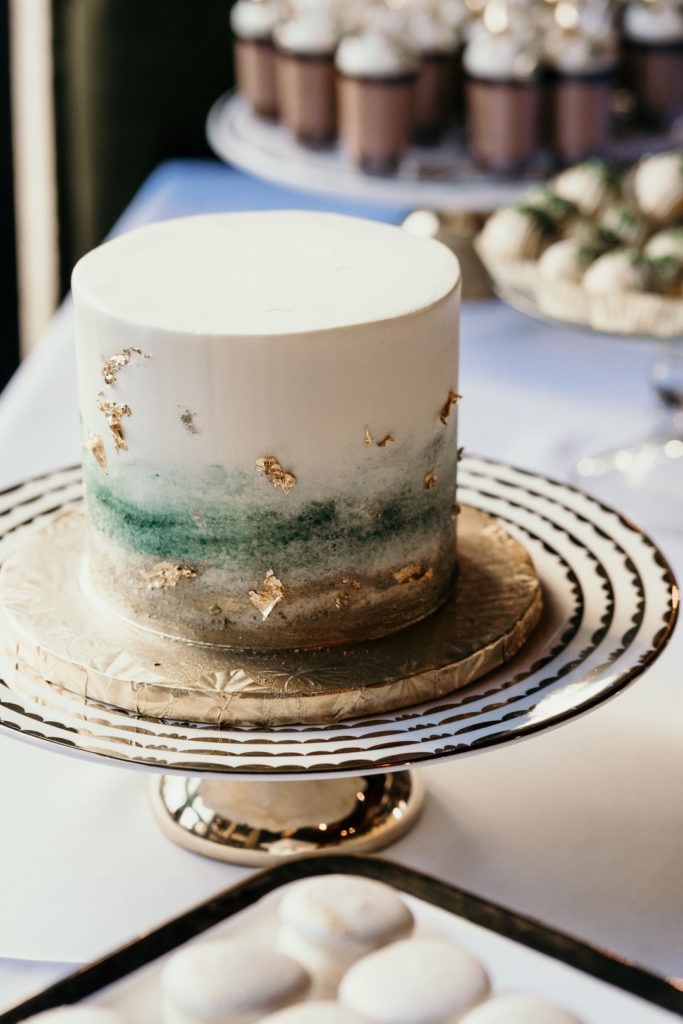 a white and green cake sitting on top of a metal tray next to cupcakes