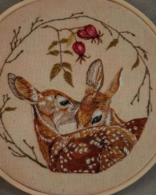 two fawns are hugging each other in the middle of a hand embroidered hoop