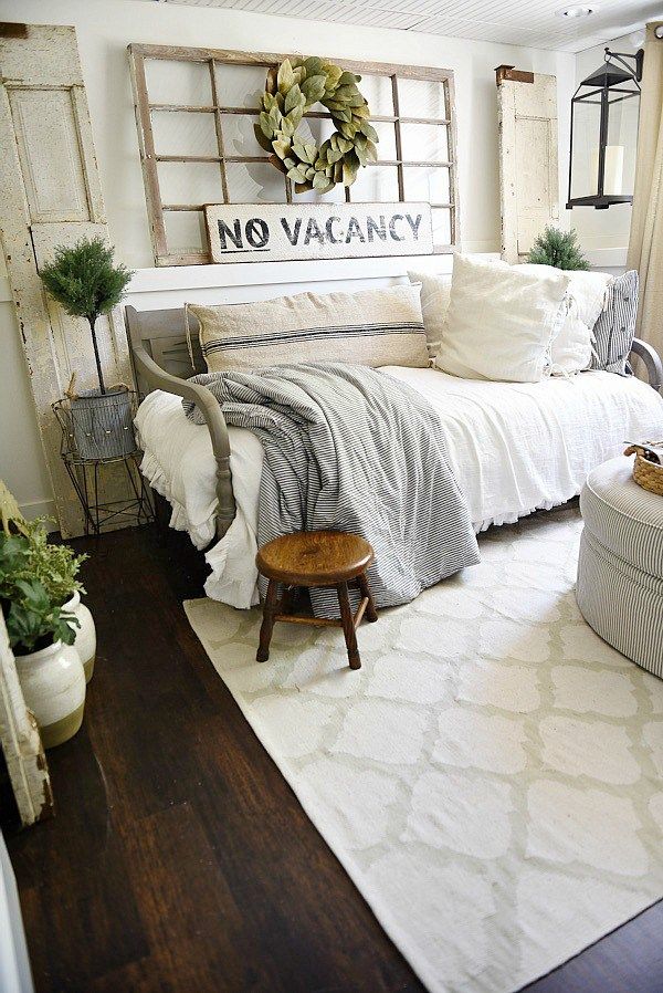 a white bed sitting next to a window on top of a wooden floor in a bedroom